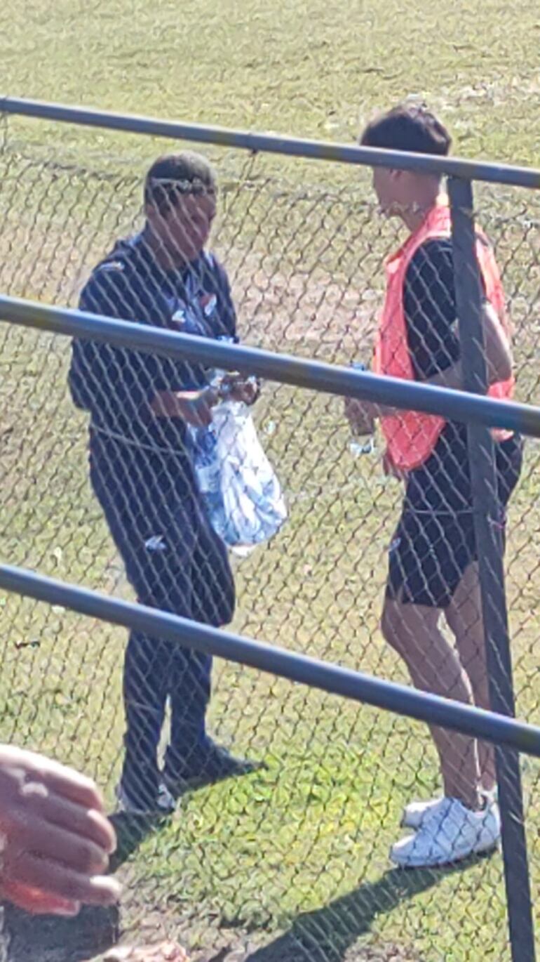 Uno de los integrantes del cuerpo técnico de la reserva de Nacional (i) y uno de los jugadores del plantel (d), mientras cargaban agua de la canilla.