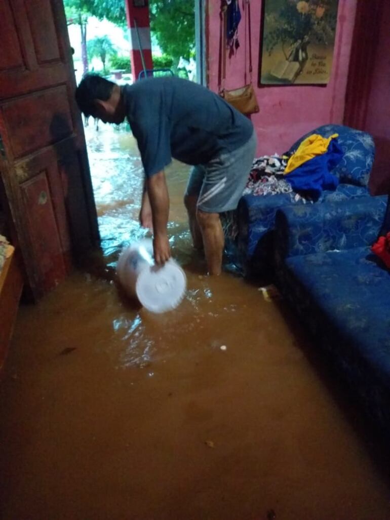 Los lugareños del barrio San Francisco de Carapeguá tratan salvar de sacar el agua que inundó sus viviendas