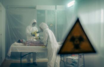 Dos personas atienden a una mujer con un virus tendida en una camilla en un hospital de campaña.