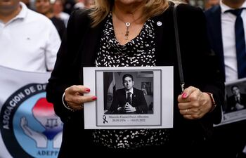 Una mujer sostiene una foto de Marcelo Pecci mientras marcha junto a cientos de personas que se suman este viernes a sendas marchas y un emotivo homenaje al fiscal antimafia Marcelo Pecci, asesinado en Colombia, en Asunción (Paraguay).