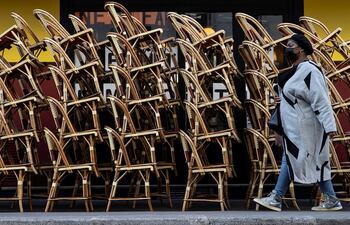 Un viandante pasa ante la terraza cerrada de un café en París.