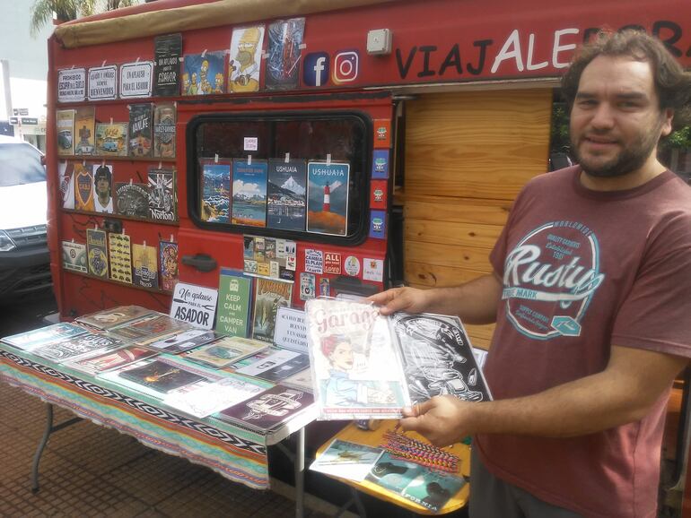 La pareja elabora artículos de artesanía, imprime camisetas, cuadros, mediante un equipo que llevan a bordo, y con el cual financian su viaje. Aquí se ve a Matías Montenegro con un cuadro elaborado por él mismo.