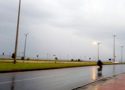 Un motociclista circula sobre el pavimento mojado por la lluvia.