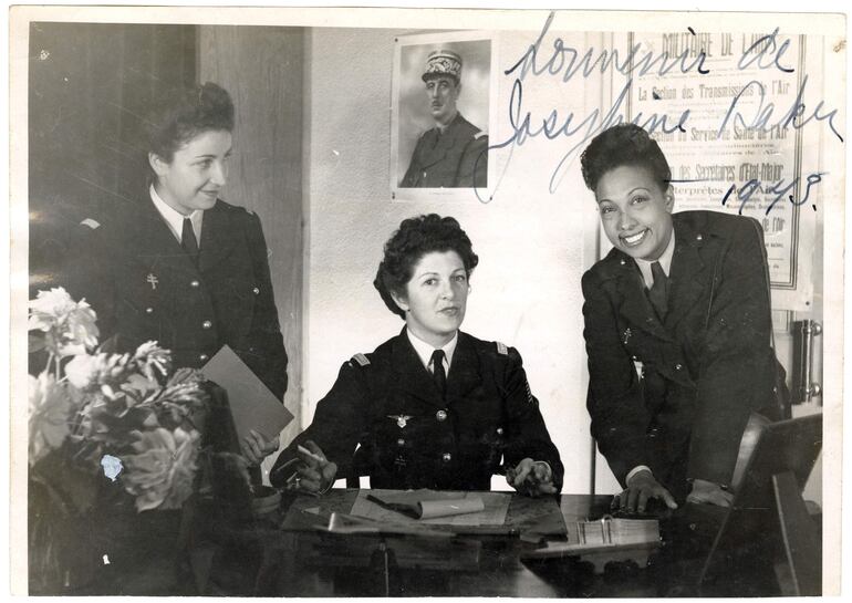 La artista con el uniforme de oficial de la Fuerza Aérea de la Francia Libre, junto con unas compañeras de armas en Argel. Al fondo, cuelga un retrato del general Charles de Gaulle, lider de las Fuerzas Francesas Libres. La fotografía tiene escrito de puño y letra: "Recuerdo de Josephine Baker, 1943".