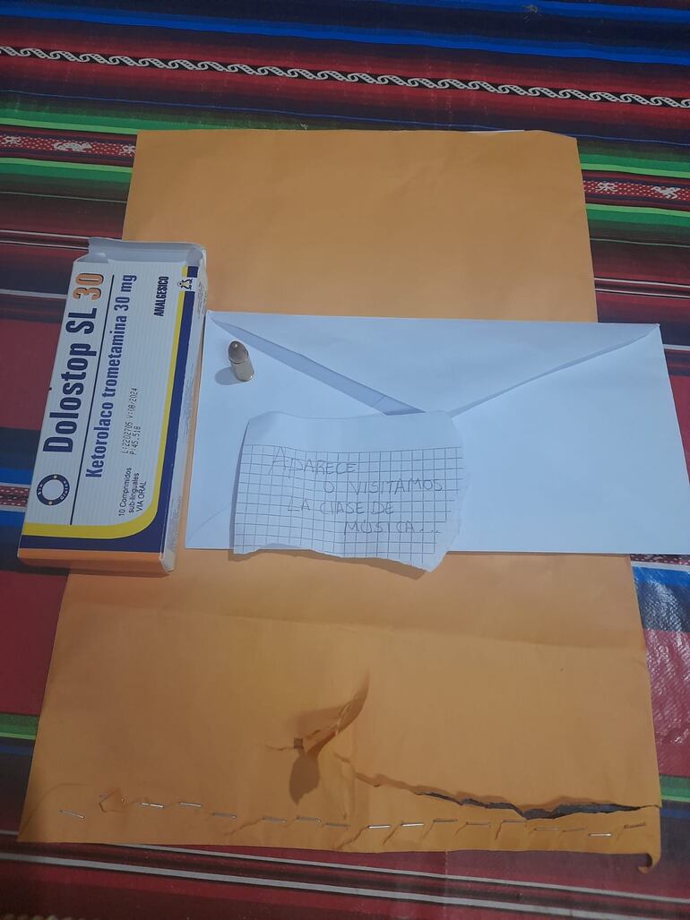 Sobre color madera, el sobre blanco, la caja de un medicamento, el mensaje en clave y una bala dejados en casa del dirigente deportivo Édgar Mónges. (gentileza).