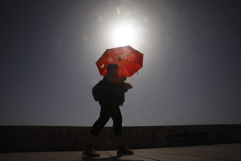 Una mujer camina resguardándose del sol con una sombrilla, hoy en Córdoba, una de las cuatro provincias andaluzas junto a Sevilla, Jaén y Granada que se encuentran en aviso naranja por temperaturas que superan los 40 grados entre las 14.00 y las 21.00 horas, según el pronóstico de la Agencia Estatal de Meteorología (Aemet).
