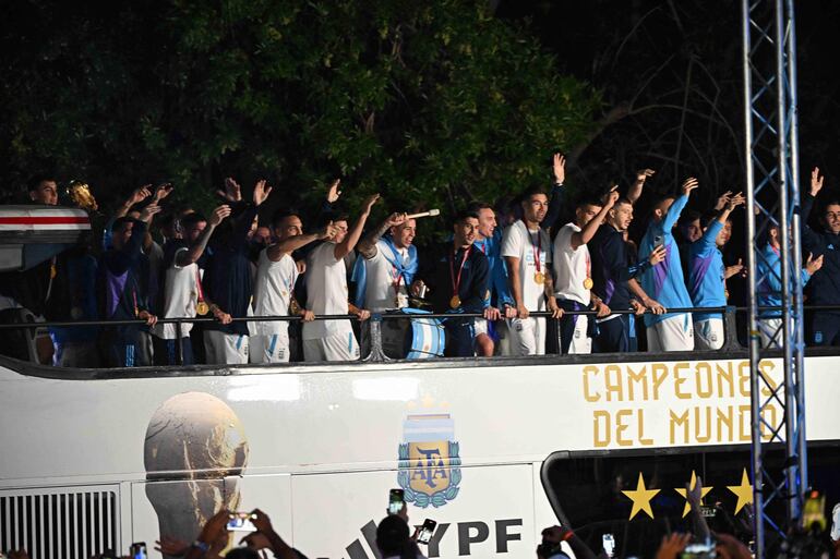 Los jugadores de la selección de Argentina a bordo del bus descapotable durante el recorrido hasta el predio de Ezeiza en compañía de miles y miles de argentinos, que recibieron al plantel en el Aeropuerto Internacional de Ezeiza después de la conquista del Mundial Qatar 2022. 