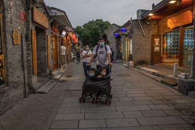 Un hombre empuja un carrito con dos niños en la calle Nanluoguxiang del barrio en Pekín, China.