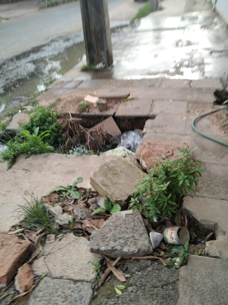 Así está la vereda del local, destrozada y con agua servida en los alrededores