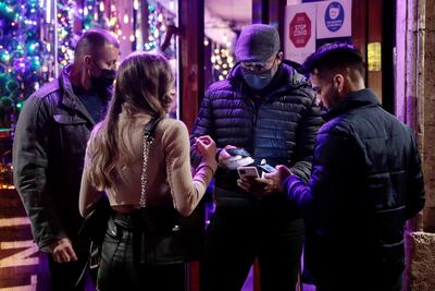 Varias personas muestran su pasaporte covid a la entrada de un local de ocio cuando ha entrado en vigor en la Comunitat Valenciana la exigencia del pasaporte covid para acceder a determinados establecimientos.