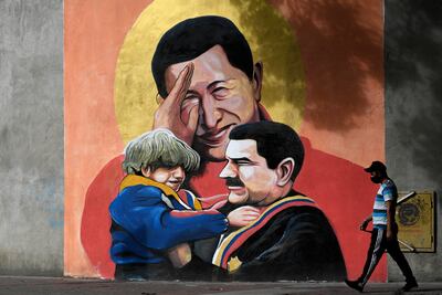 Un hombre camina junto a un mural que muestra al presidente venezolano Nicolás Maduro y al expresidente Hugo Chávez, en Caracas.