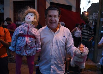 Un hombre con una careta de Horacio Cartes participa de las manifestaciones contra el gobierno. En una mano lleva una muñeca con el rostro de la fiscala Sandra Quiñónez y en la otra un muñeco de peluche con la cara del presidente Mario Abdo Benítez. (archivo)
