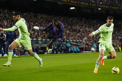 El delantero del Barcelona Ousmane Dembelé (c) cae entre Omar Alderete (i) y Juan Iglesias, ambos del Getafe, durante el partido de Liga en Primera División que FC Barcelona y Getafe CF disputan este domingo en el Camp Nou. EFE/Enric Fontcuberta