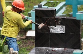Fotografía cedida por la presidencia de El Salvador en la que se observa a un funcionario destruye símbolos e imágenes alusivas a miembros de las pandillas Mara Salvatrucha (MS-13) en el cementerio de Santa Tecla. (AFP)