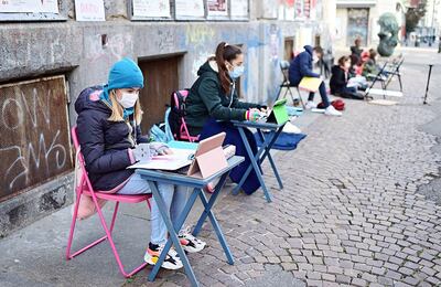 Anita Iacovelli (izq.), de 12 años, se sienta todos los días frente a su escuela, a estudiar; luego le acompaña su amiga, Lisa Rogliatti (der.), y ahora se han sumado otros alumnos más (al fondo).