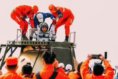 El astronauta chino Ye Guangfu (C) es asistido por funcionarios para salir de la cápsula de la nave espacial Shenzhou-13 después de aterrizar en Mongolia Interior de China el 16 de abril de 2022.