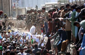 Numerosos afganos muestran credenciales mientras intentan contactar con las fuerzas internacionales para intentar huir del país, este jueves en los exteriores del aeropuerto Hamid Karzai de Kabul. Al menos 15 personas murieron y otras 60 resultaron heridas en dos explosiones fuera del aeropuerto de Kabul.