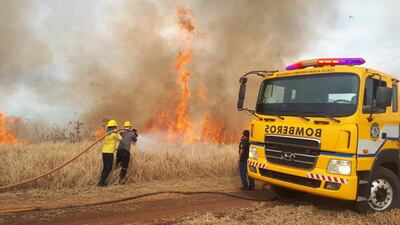 Los bomberos combaten el fuego en los pastizales dentro del predio del aeropuerto.