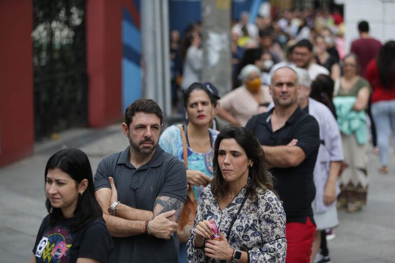 Ciudadanos esperan en una fila para votar hoy, en Río de Janeiro (Brasil). Los electores llegaron a esperar hasta 3 horas para sufragar debido a la alta participación. (EFE)