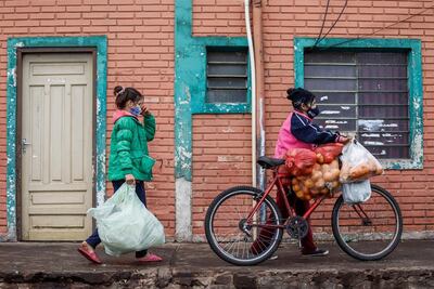 Dos mujeres con tapabocas trasladan sus compras este jueves, en el Mercado de Abasto de Asunción (Paraguay).