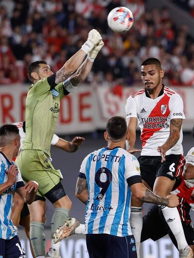 Héctor David Martínez, jugador paraguayo de River Plate, salta en procura del balón ante el arquero chileno Gabriel Arias, de Racing Club.