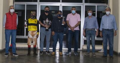 El jockey Juan Ramírez, Alfredo Halley y César Paredes, representantes del Stud El Legendario, con las copas “Don Pelayo Abente”, en medio de los directivos.