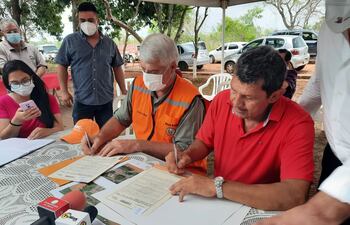 Momento en que el titular del MOPC, Arnoldo Wiens, y el representante de los pobladores de Potrero Kue, Diosnel López, firman el acta de acuerdo de las obras propuestas.