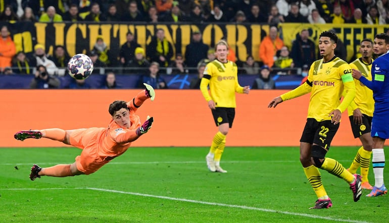 El portero español del Chelsea, Kepa Arrizabalaga (L), se zambulló por el balón frente al mediocampista inglés de Dortmund, Jude Bellingham, durante el partido de fútbol BVB Borussia Dortmund vs Chelsea FC en Dortmund, Alemania occidental, el 15 de febrero de 2023.