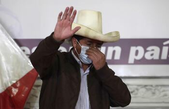 El candidato presidencial peruano Pedro Castillo saluda mientras acomoda su tapabocas durante una rueda de prensa.