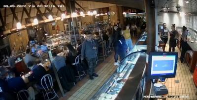 Momento en que el sospechoso toma la cartera colgada por el respaldo de una silla en El Bolsi.