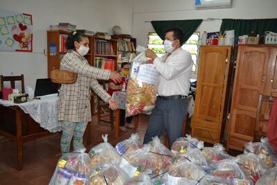 El director de Escuela Maestros Rurales, César Morínigo, hace entrega de kits a una madre de familia.