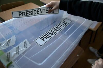 Una mujer coloca una calcomanía que dice "Presidente" en una urna durante el montaje de los colegios electorales de la escuela secundaria Portugal en Punta Arenas, Chile, el 20 de noviembre de 2021, en vísperas de las elecciones generales de Chile.