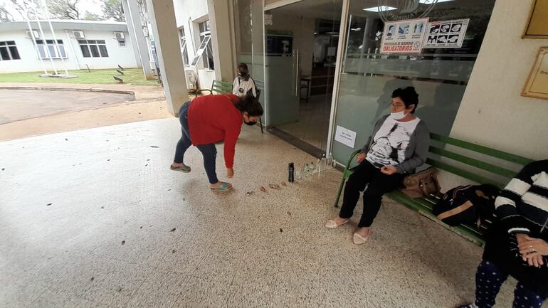 Momento en que una asegurada del IPS deja sus pertenencias en un fila de cosas para reservar su turno en consultorios. 