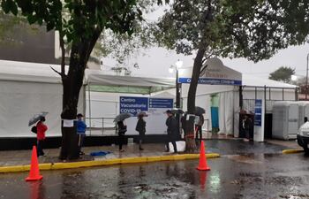 Las personas formando fila bajo la lluvia en el vacunatorio del Sanatorio Británico.