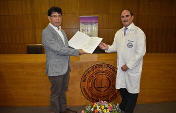 El Prof. Dr. Laurentino Barrios, decano saliente, entrega la resolución de su nombramiento al nuevo decano de la FCM-UNA, Prof. Dr. Osmar Cuenca Torres.