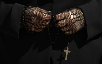 Una participante en la Cofradía del Santo Entierro sostiene un rosario durante la procesión de "La Soledad ", esta mañana por las calles de Oviedo. EFE/Eloy Alonso.