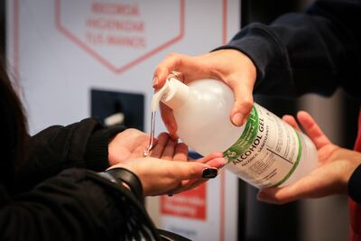 Personas se ponen alcohol en gel en las manos este martes para entrar a un centro comercial.