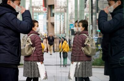 Transeúntes con máscaras protectoras se reflejan en un escaparate en Tokio.