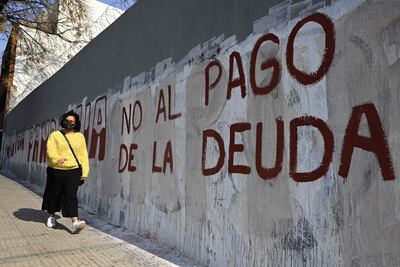 Una mujer camina junto a un muro pintado con la leyenda "No al pago de la deuda", en Argentina.
