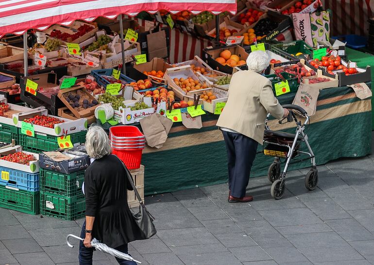 Una mujer mayor se dispone a comprar frutas y verduras en un mercado semanal en Alemania.