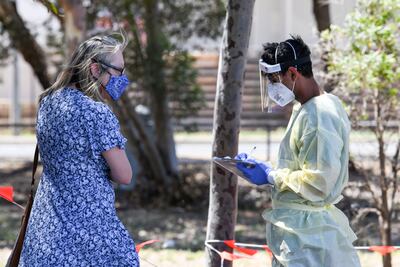 Un trabajador médico conversa con una mujer en el aeropuerto Parafield de Adelaida, Australia.