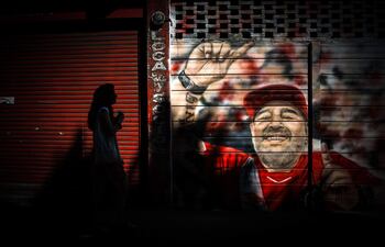 Una mujer camina frente a un mural sobre Diego Armando Maradona en el estadio de Argentinos Juniors. Ayer, a 61 años del nacimiento del astro del fútbol mundial, fallecido el pasado noviembre, los argentinos realizarán varios homenajes para conmemorar al ídolo deportivo.