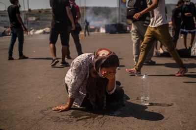 Una mujer se limpia los ojos con agua luego de haber sido alcanzada por gas lacrimógeno en un enfrentamiento entre manifestantes y policías en la isla de Lesbos.