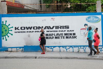 Personas sin mascarillas caminan frente a un mural alusivo al coronavirus,en Puerto Príncipe (Haití).
