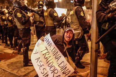 Una persona grita arengas junto a miembros de la Policía mientras sostiene un cartel contra la presidenta Dina Boluarte, durante una manifestación en los exteriores de Palacio de Justicia en Lima (Perú).