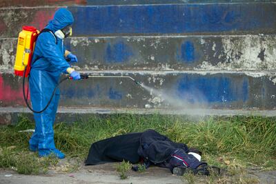 Un miembro del equipo de Criminalística y Ciencias Forenses lleva adelante un procedimiento de rutina con el cadáver de un hombre supuestamente muerto por coronavirus, en una calle del sur de Quito, Ecuador.