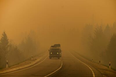 Los coches circulan por una carretera cubierta de humo de los incendios forestales cercanos, entre el pueblo de Magaras y la ciudad de Yakutsk, en la república de Sakha, Siberia.