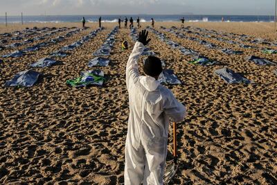 Un grupo de personas trabaja al amanecer para preparar el acto de la ONG Río de Paz en memoria de los más de 400.000 brasileños muertos por el Covid-19, este viernes en las arenas de la playa de Copacabana, en la zona sur de Río de Janeiro, Brasil. El país superó ayer la barrera de las 400.000 muertes por covid-19, con los hospitales aún en una situación "crítica" y bajo el riesgo de sufrir una tercera ola de la pandemia, pese a la tímida desaceleración de las últimas dos semanas.