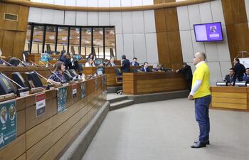 El diputado Basilio "Bachi" Núñez (ANR, HC) incita a su colega Celeste Amarilla (PLRA) mientras esta hace uso de palabra. Apareció en la sesión con una remera amarilla con la leyenda "coimeadas conmigo".