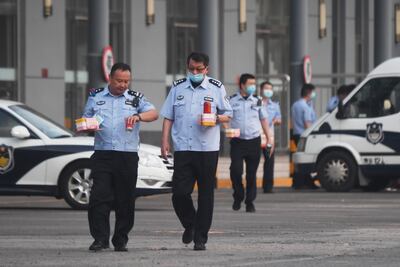 Los agentes de policía transportan alimentos mientras caminan por los terrenos de una estación de autobuses cerrada cerca del mercado cerrado de Xinfadi en Beijing.